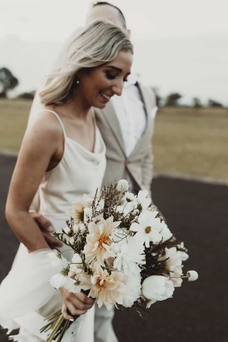Bride and groom walking down pathway holding bouquet