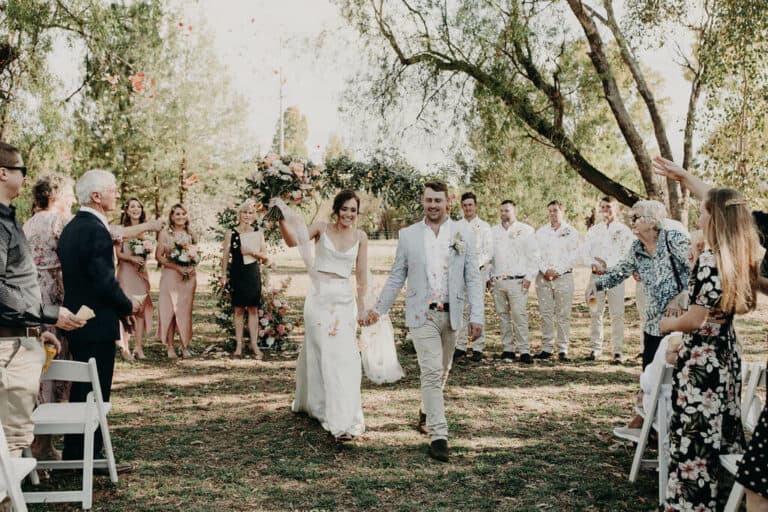 Bride and groom walking down aisle with guests throwing confetti