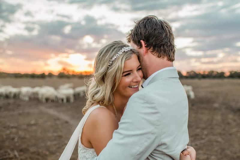 Bride and groom hugging in paddock at sunset