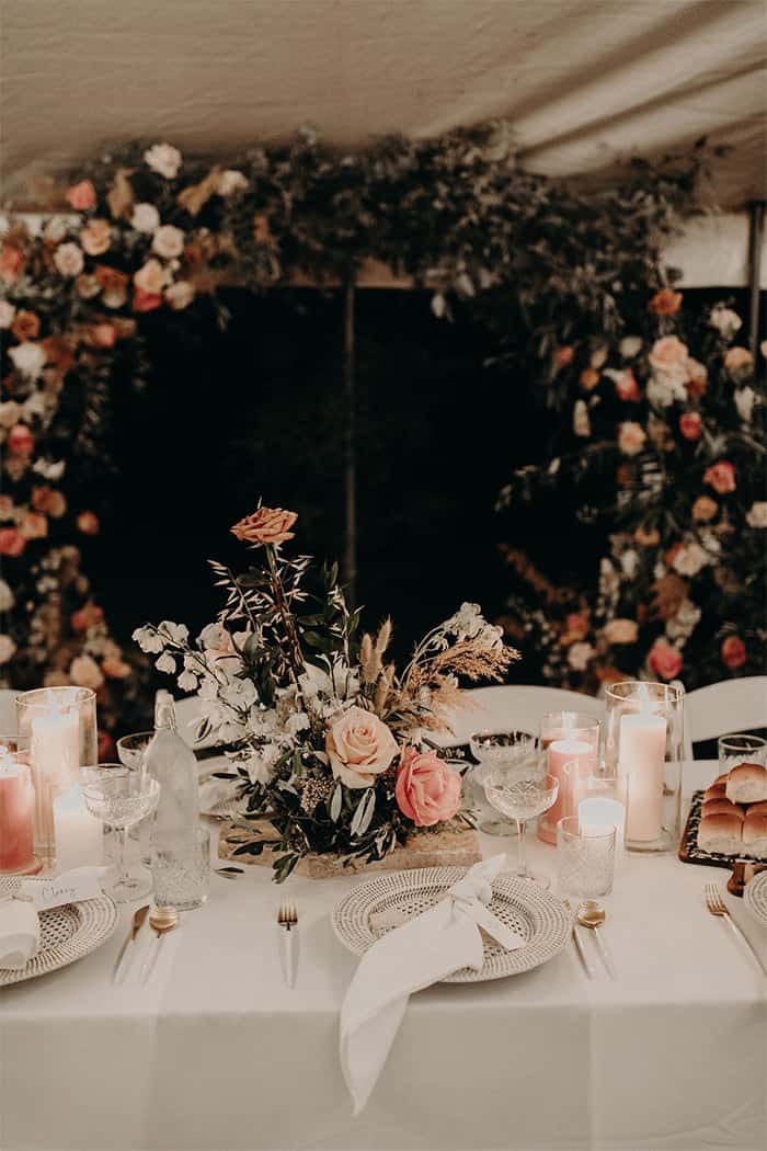 Table set up for wedding with pink and peach floral arrangements and candles