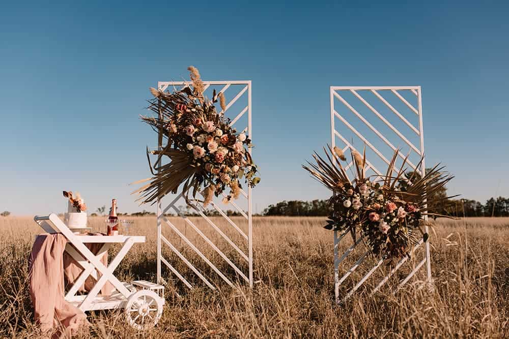 Floral arrangements against wooden backdrops with a drinks cart standing in a field
